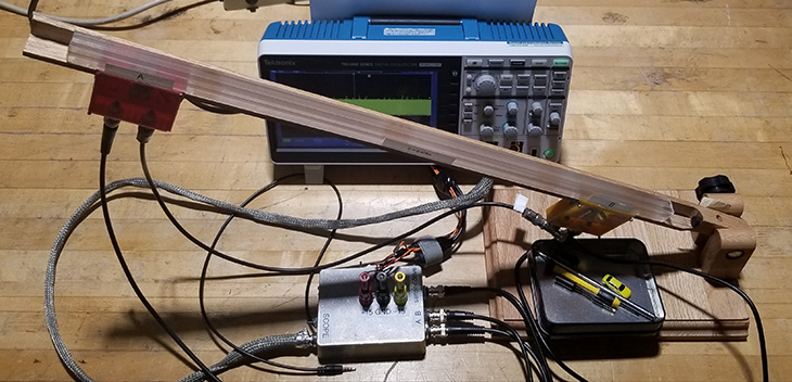 An incline with two magnetometers placed at its ends. The excitation and signal analysis is done by a compact hardware box visible under the incline.